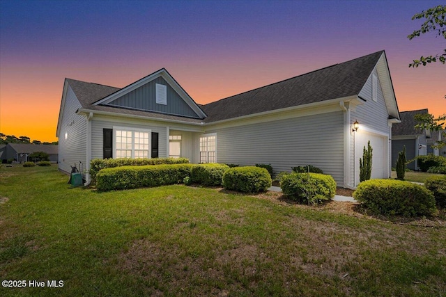 ranch-style house with an attached garage, board and batten siding, and a lawn