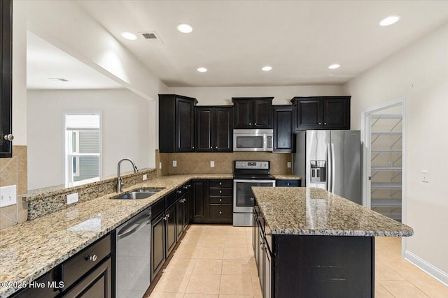 kitchen with visible vents, decorative backsplash, light stone countertops, a sink, and stainless steel appliances