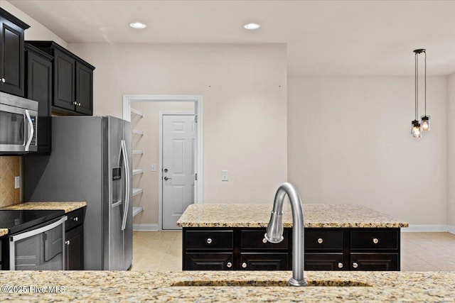 kitchen with dark cabinets, light tile patterned floors, and stainless steel appliances
