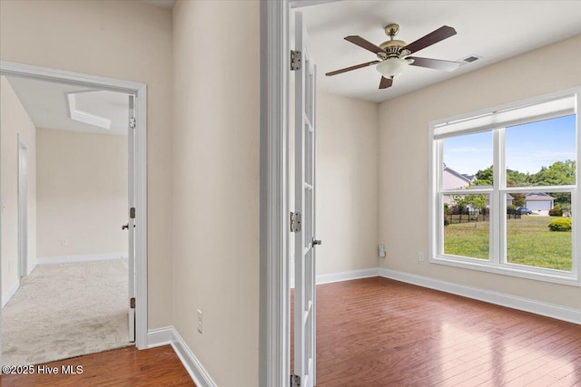 empty room featuring a ceiling fan, baseboards, visible vents, and wood finished floors