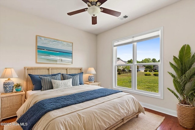 bedroom featuring ceiling fan, baseboards, visible vents, and wood finished floors