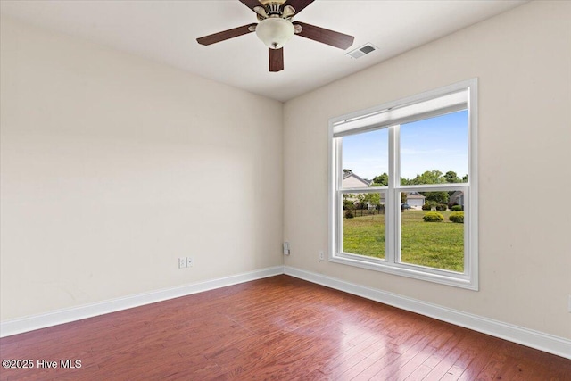 spare room featuring baseboards, plenty of natural light, wood finished floors, and visible vents