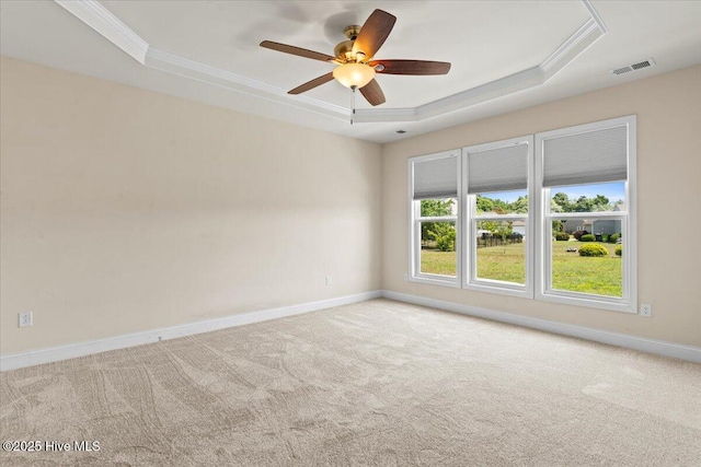 carpeted empty room featuring a ceiling fan, visible vents, crown molding, baseboards, and a tray ceiling