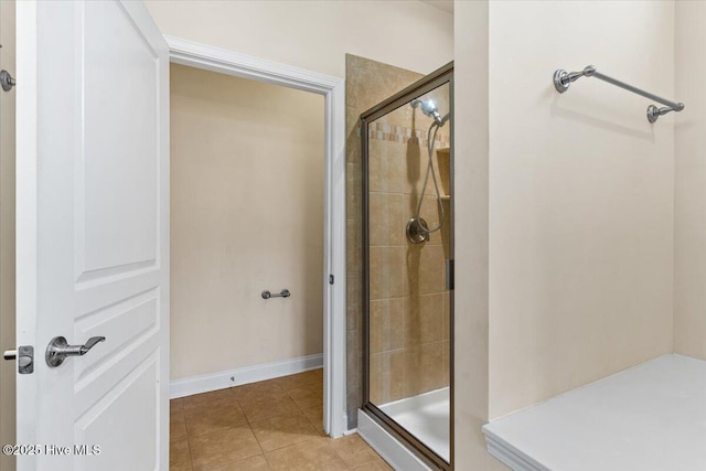 bathroom featuring baseboards, tile patterned flooring, and tiled shower