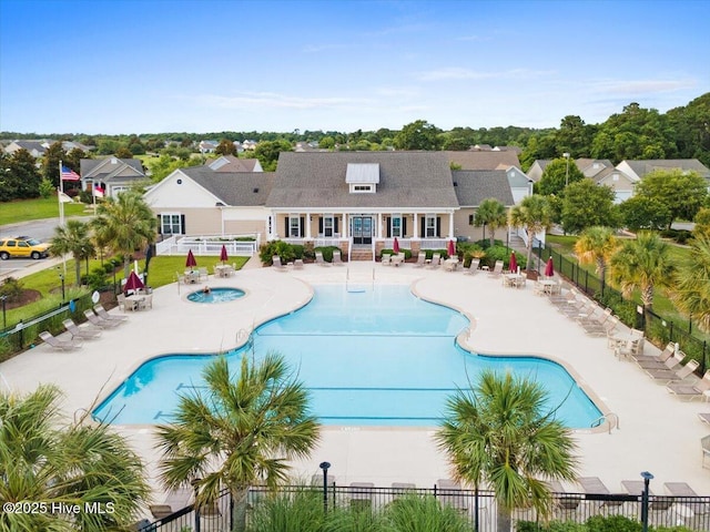 community pool featuring a patio, a community hot tub, fence, and a residential view