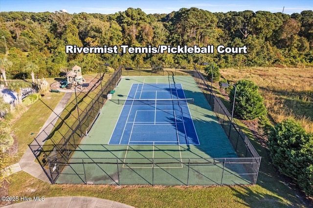 view of sport court featuring fence and a wooded view