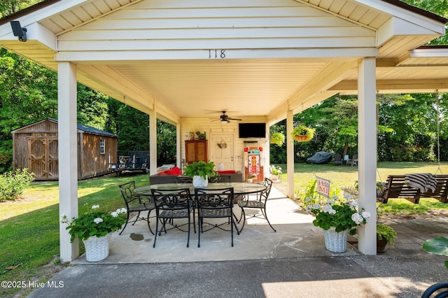 view of patio featuring a storage shed, a ceiling fan, outdoor dining space, and an outbuilding
