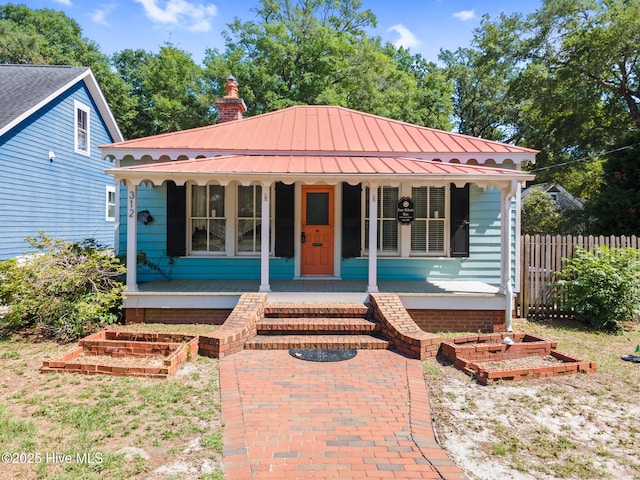 312 E W St, Southport, NC 28461 - view of front of home featuring covered porch, a garden, and a chimney