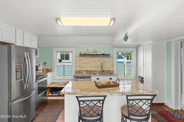 312 E W St, Southport, NC 28461 - kitchen with stainless steel appliances, a sink, white cabinetry, decorative backsplash, and a breakfast bar area
