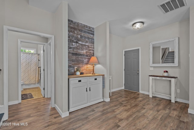 foyer featuring dark wood-style flooring, baseboards, and bar