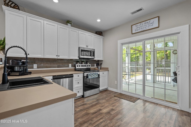 kitchen with appliances with stainless steel finishes, a sink, decorative backsplash, light countertops, and recessed lighting
