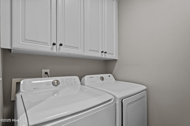 washroom with washer and clothes dryer and cabinet space