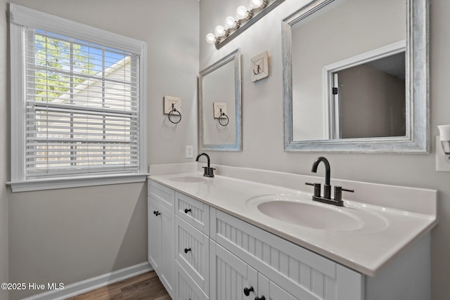 bathroom with wood finished floors, double vanity, and baseboards