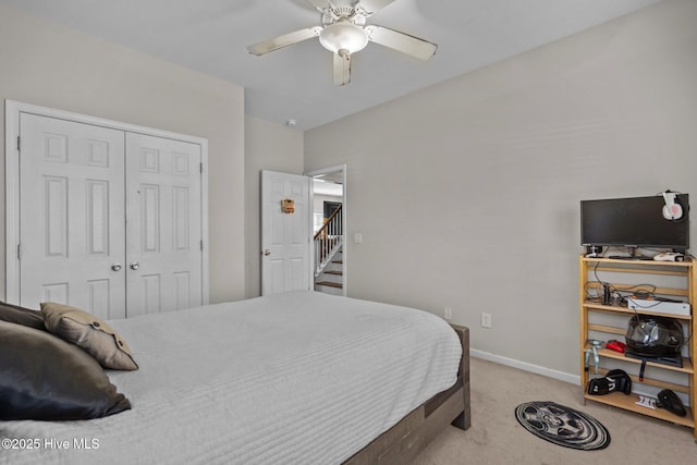 bedroom featuring light carpet, a closet, a ceiling fan, and baseboards