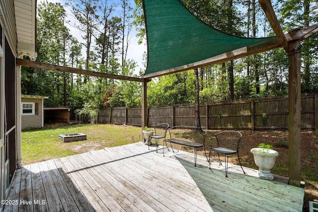 wooden terrace with an outdoor fire pit and view of wooded area