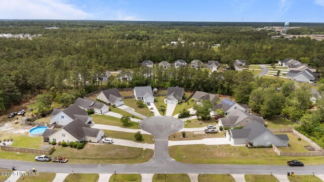 aerial view of property and surrounding area featuring a forest, nearby suburban area, and a pool