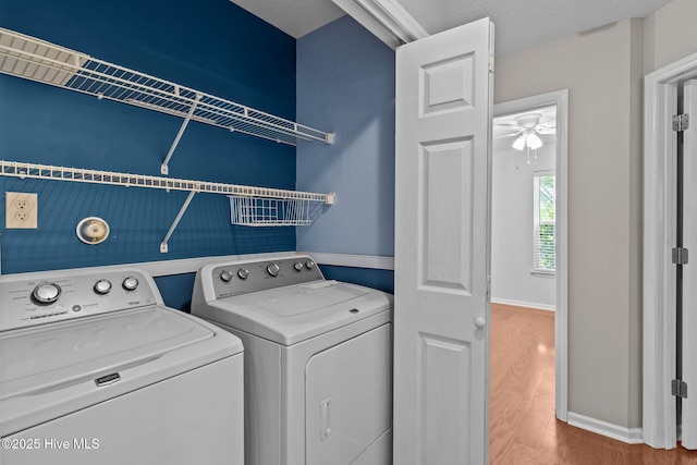 washroom with laundry area, washing machine and dryer, wood finished floors, baseboards, and a ceiling fan