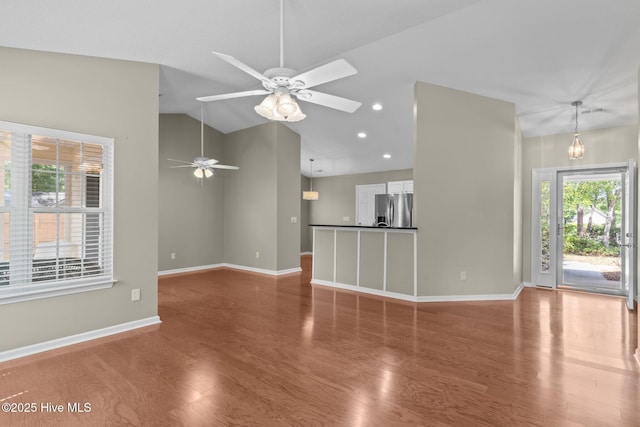 unfurnished living room featuring baseboards, a ceiling fan, lofted ceiling, and wood finished floors