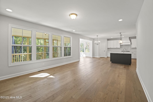 231 Dona Dr, Carthage, NC 28327 - unfurnished living room with a chandelier, baseboards, recessed lighting, wood finished floors, and a sink