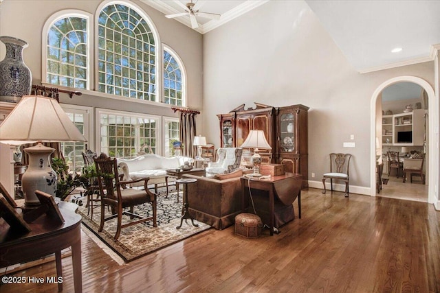 living room with arched walkways, ornamental molding, and wood finished floors
