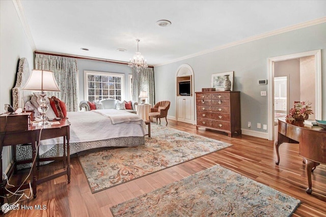 bedroom with an inviting chandelier, ornamental molding, baseboards, and wood finished floors
