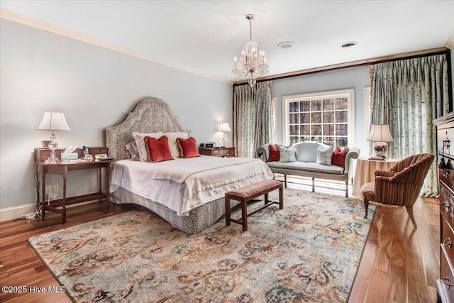 bedroom with visible vents, ornamental molding, wood finished floors, baseboards, and a notable chandelier