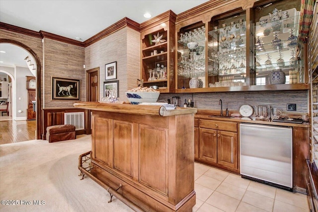 bar with crown molding, arched walkways, a sink, indoor wet bar, and dishwashing machine