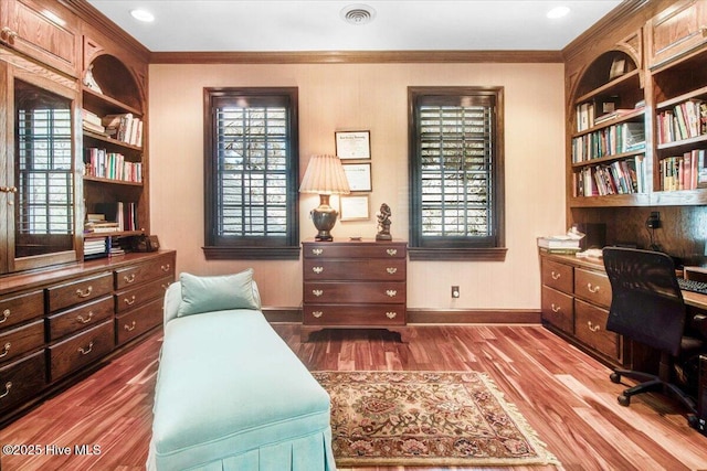 home office featuring crown molding, visible vents, wood finished floors, baseboards, and built in study area