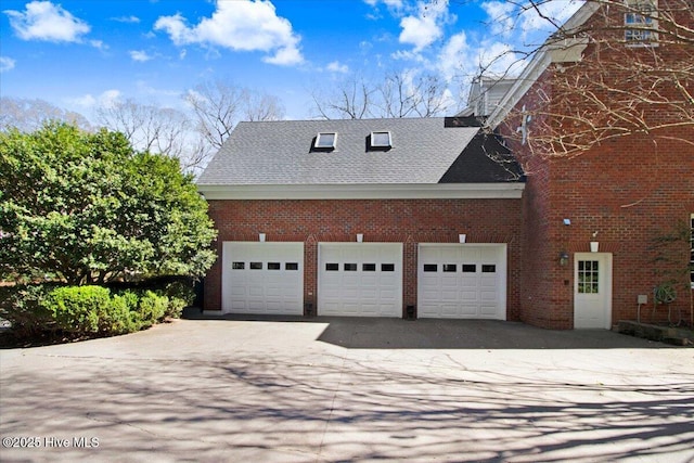 view of home's exterior featuring roof with shingles, a garage, brick siding, and aphalt driveway
