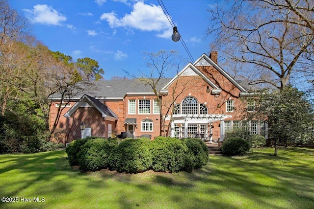 rear view of property featuring brick siding, a pergola, a chimney, and a lawn