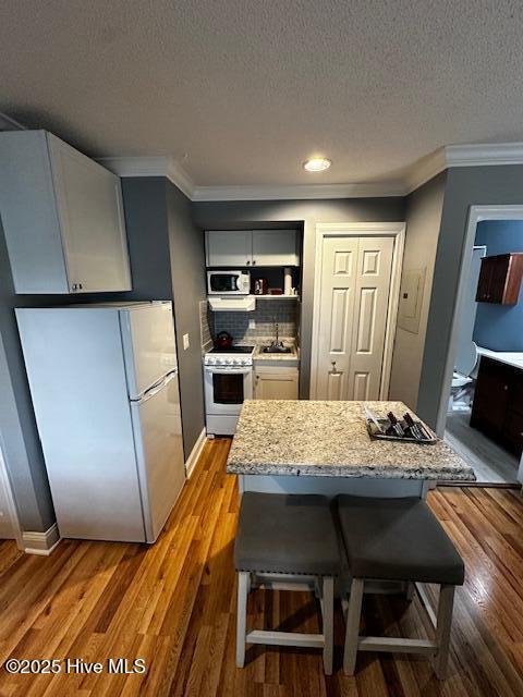 6214 Harbourside Dr, New Bern, NC 28560 - kitchen featuring a textured ceiling, a breakfast bar, white appliances, a sink, and crown molding