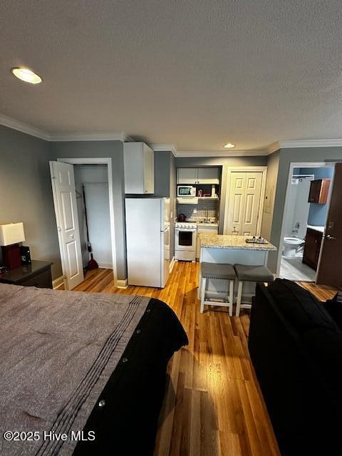 6214 Harbourside Dr, New Bern, NC 28560 - bedroom featuring freestanding refrigerator, a closet, light wood-type flooring, a textured ceiling, and ornamental molding