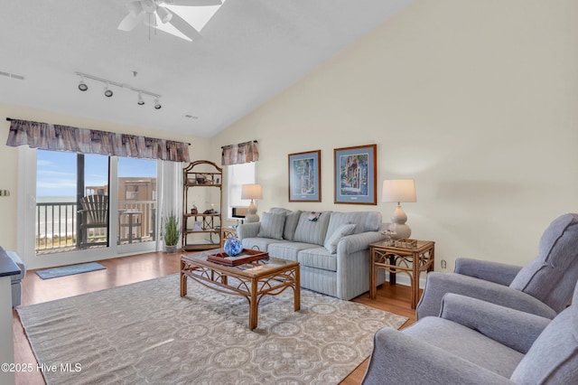 living area with track lighting, ceiling fan, vaulted ceiling, and wood finished floors