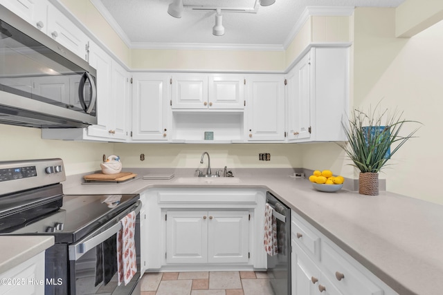 kitchen featuring light countertops, white cabinetry, rail lighting, a sink, and stainless steel appliances