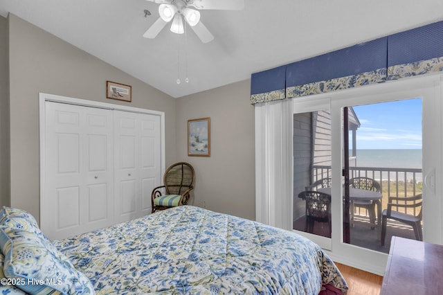 bedroom with a ceiling fan, vaulted ceiling, wood finished floors, a water view, and access to outside