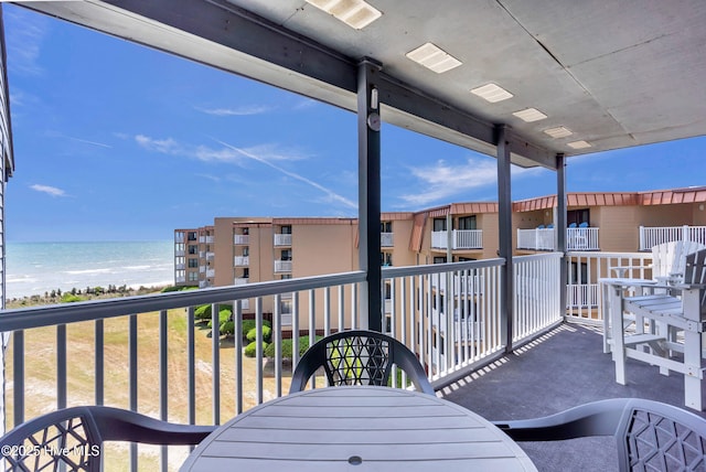 balcony featuring a water view, outdoor dining area, and visible vents