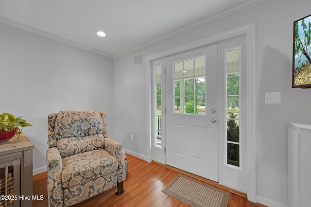 foyer entrance featuring crown molding, baseboards, visible vents, and wood finished floors