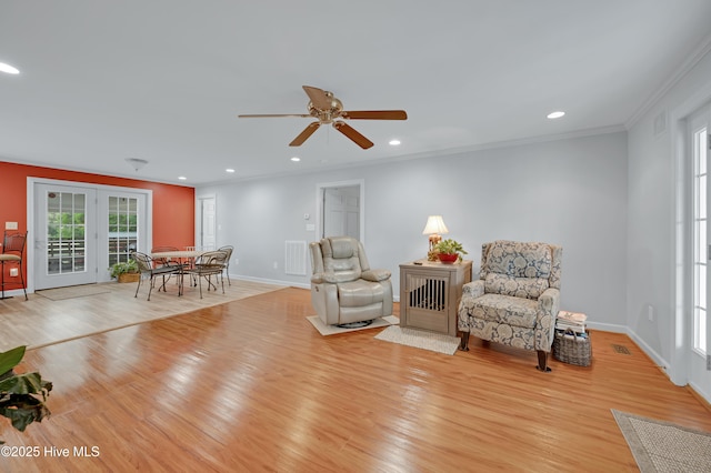 living area featuring crown molding, baseboards, ceiling fan, and light wood-style floors