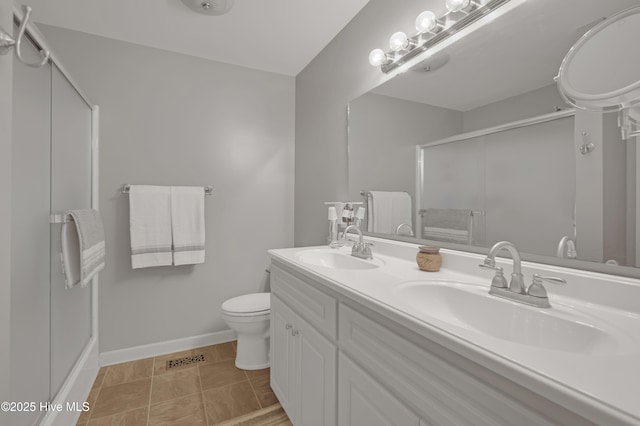 full bathroom with toilet, baseboards, a shower stall, and a sink