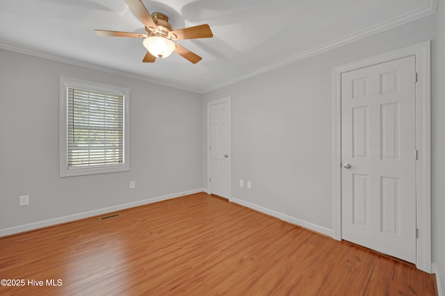 empty room featuring crown molding, ceiling fan, visible vents, and light wood-style flooring