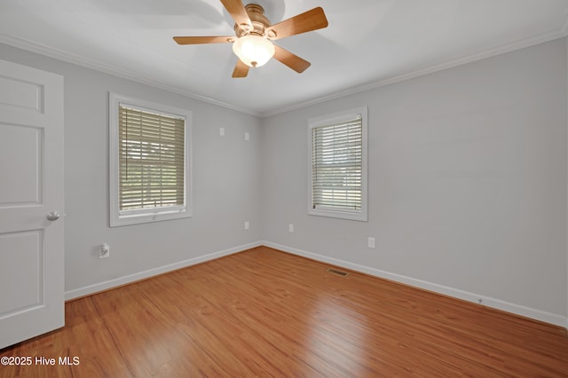 spare room with light wood-style floors, a ceiling fan, baseboards, visible vents, and ornamental molding
