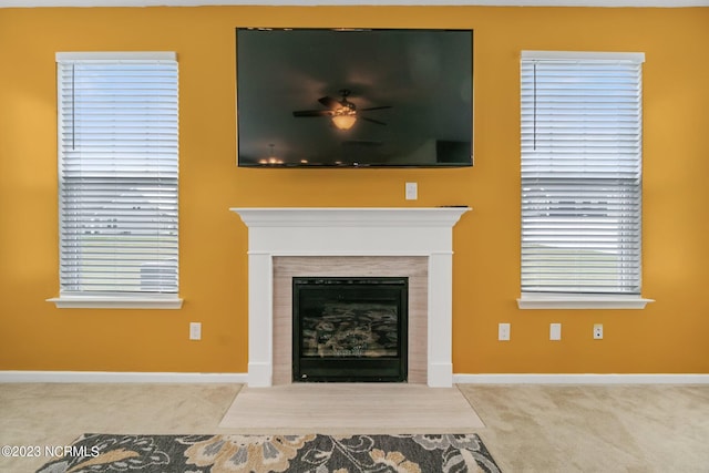 unfurnished living room with baseboards, a wealth of natural light, ceiling fan, a fireplace with flush hearth, and carpet floors