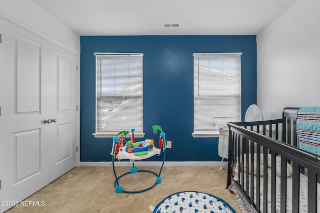 carpeted bedroom featuring a crib, visible vents, and baseboards