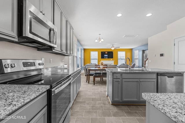 kitchen with appliances with stainless steel finishes, gray cabinets, a healthy amount of sunlight, and a sink