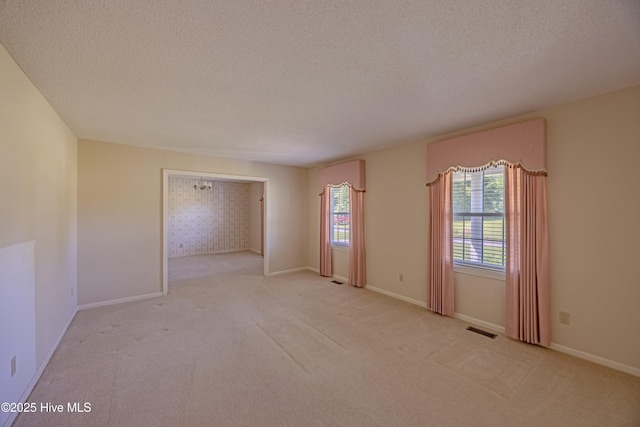 carpeted spare room with a textured ceiling, visible vents, and a wealth of natural light