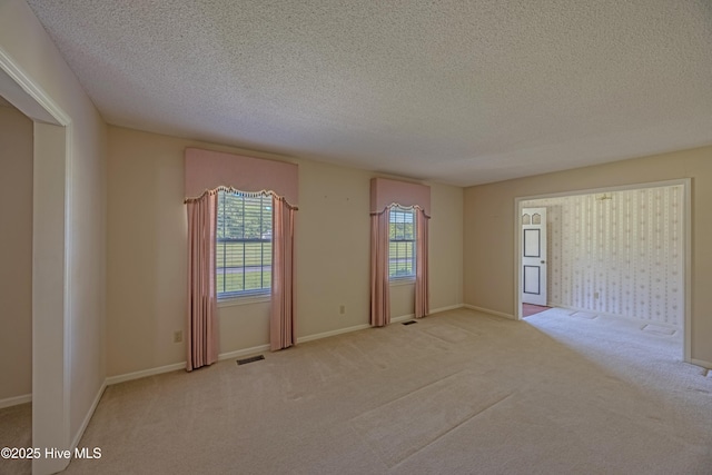 carpeted empty room featuring visible vents and a textured ceiling
