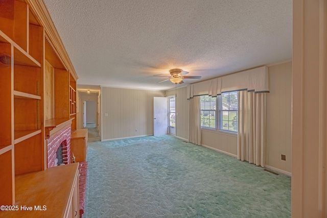 carpeted spare room with baseboards, a ceiling fan, a textured ceiling, and visible vents