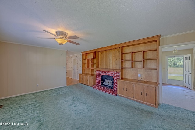 unfurnished living room with ornamental molding, a fireplace, a textured ceiling, a ceiling fan, and carpet