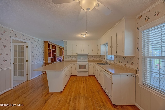 kitchen featuring a peninsula, a textured ceiling, light wood-style flooring, and white electric range