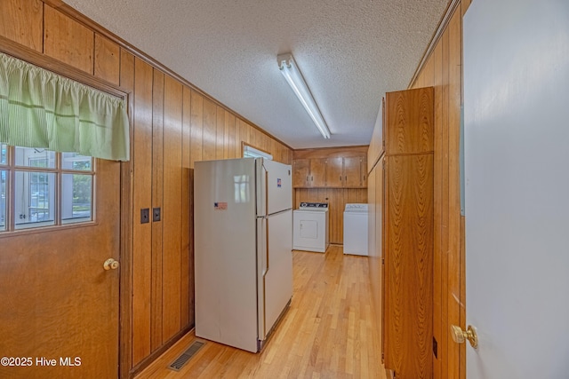 kitchen with visible vents, freestanding refrigerator, a textured ceiling, light wood finished floors, and independent washer and dryer